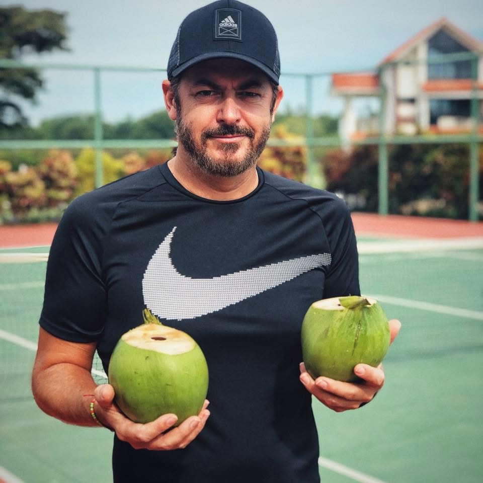 Marc Mulvaney holding two fresh coconuts on a tennis court in Panama, 2018
